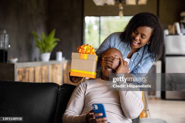 donna a casa che sorprende suo marito con un regalo - regalo di compleanno foto e immagini stock