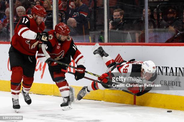Fabian Zetterlund of the New Jersey Devils falls to the ice as he attempts to play the puck against Alex Galchenyuk and Shayne Gostisbehere of the...