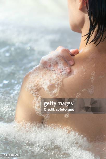 femme se relaxant tout en prenant une douche dans la baignoire jacuzzi - beautiful woman bath photos et images de collection