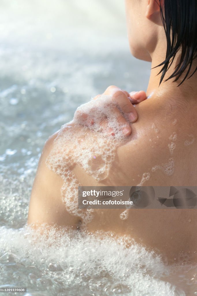 Woman relaxing while taking a shower in hot tub tub