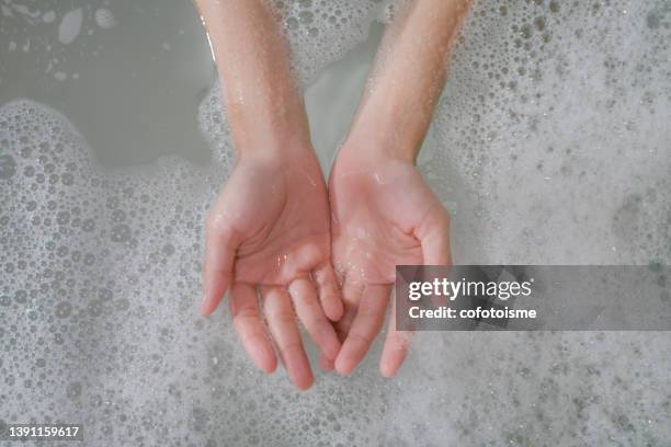 close up woman hand with fizzy bubble in bathtub - bath bomb stock pictures, royalty-free photos & images