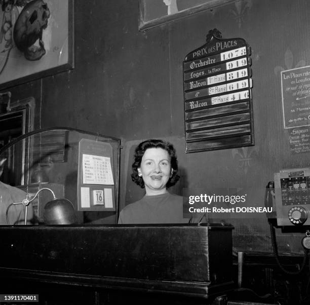 La caissière du Grand Guignol derrière son comptoir et affichage des prix des places derrière elle en février 1957 à Paris.