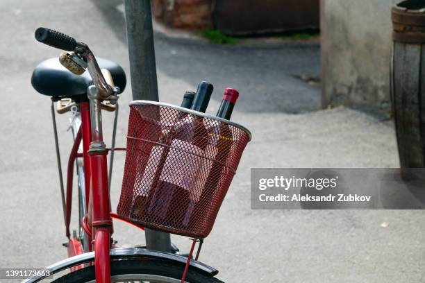 an old rusty stylish retro bike with a basket leaning against a pole, on a georgia street, on a sunny summer day. the concept of an environmentally friendly healthy sustainable lifestyle. bottles of wine in the basket. purchase or delivery of products. - wine home delivery stock pictures, royalty-free photos & images