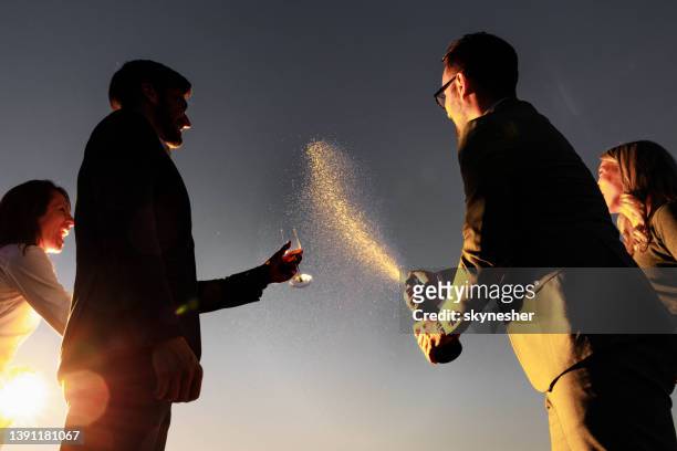 opening champagne against the sky at sunset! - wine splashing stock pictures, royalty-free photos & images
