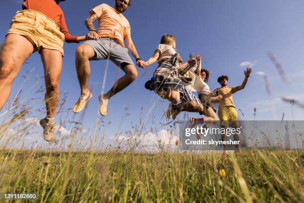 below view of playful friends jumping in spring day. - large group of people field stock pictures, royalty-free photos & images