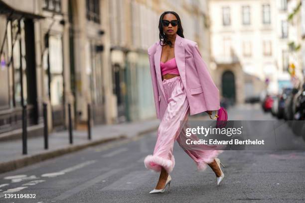 Emilie Joseph @in_fashionwetrust wears black sunglasses, silver rhinestones earrings, a pink ribbed cross-strappy V-neck / cropped tank-top, a pale...