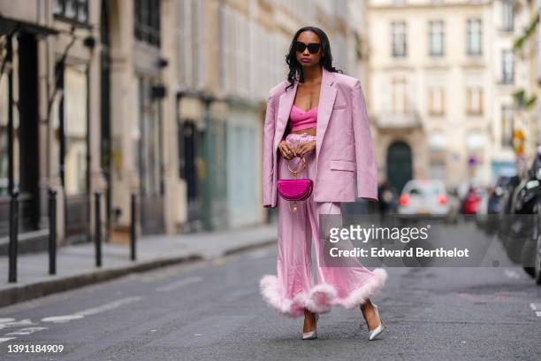 Emilie Joseph @in_fashionwetrust wears black sunglasses, silver rhinestones earrings, a pink ribbed cross-strappy V-neck / cropped tank-top, a pale...