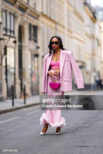 Emilie Joseph @in_fashionwetrust wears black sunglasses, silver rhinestones earrings, a pink ribbed cross-strappy V-neck / cropped tank-top, a pale...