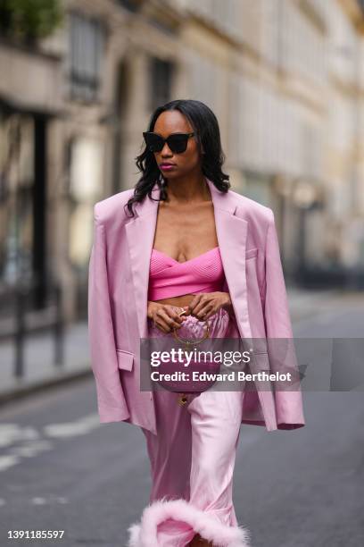 Emilie Joseph @in_fashionwetrust wears black sunglasses, silver rhinestones earrings, a pink ribbed cross-strappy V-neck / cropped tank-top, a pale...