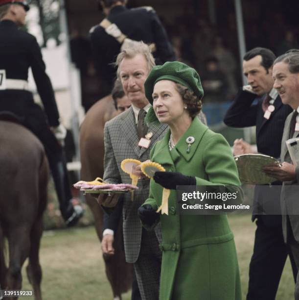 Queen Elizabeth II, wearing a green coat and matching hat, awards rosettes at the Royal Windsor Horse Show, held at Home Park in Windsor, Berkshire,...