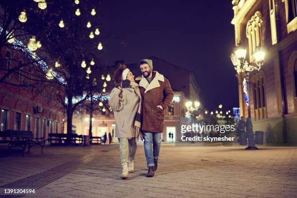 glückliches umarmtes paar, das nachts auf der stadtstraße plaudert. - evening walk stock-fotos und bilder