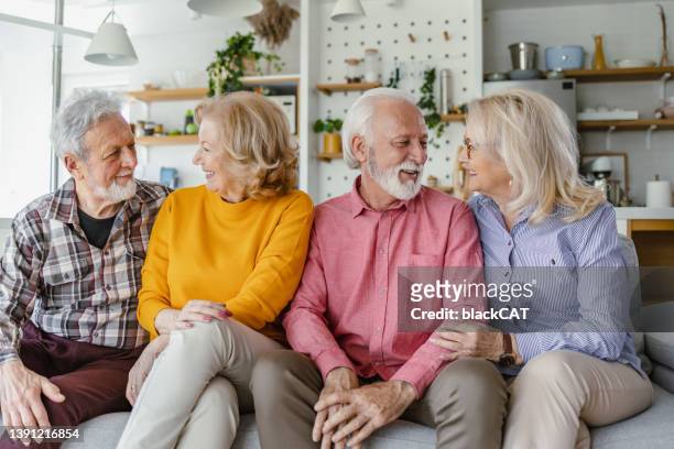 cuatro sonrientes amigos mayores en casa - psychiatrists couch fotografías e imágenes de stock