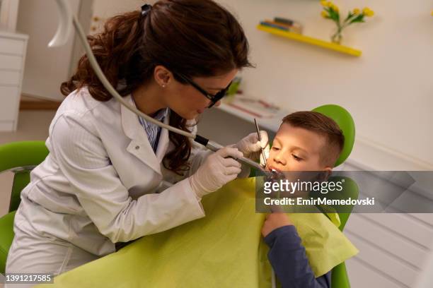 dentista femenino que da el llenado de dientes de paciente masculino joven - suction tube fotografías e imágenes de stock