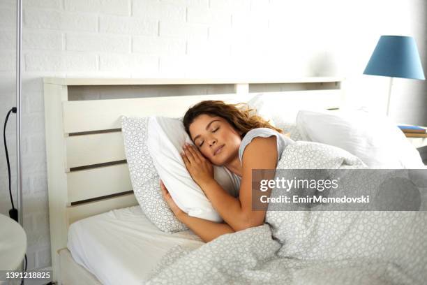 giovane donna che dorme pacificamente nel suo letto - solo una donna di età media foto e immagini stock
