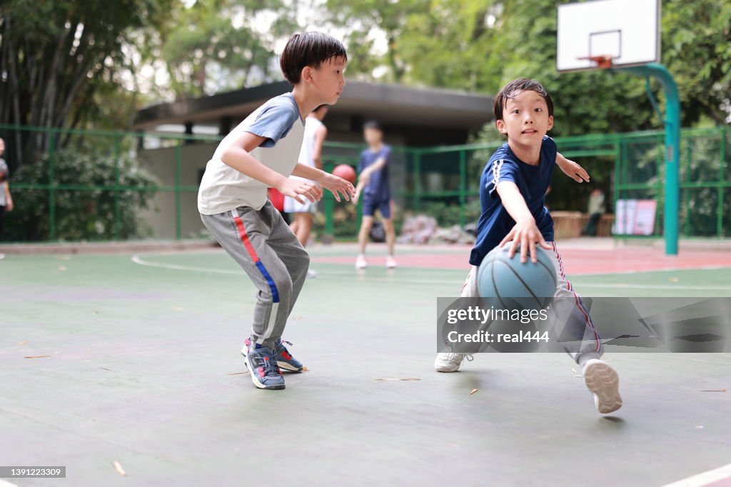 Two boys playing basketball outside