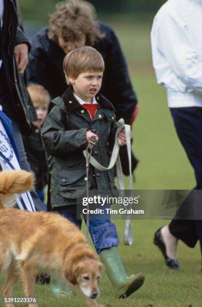 British Royal Prince William, wearing a waxed jacket and wellington boots, walking a dog in the grounds of Cirencester Park Polo Club on the...