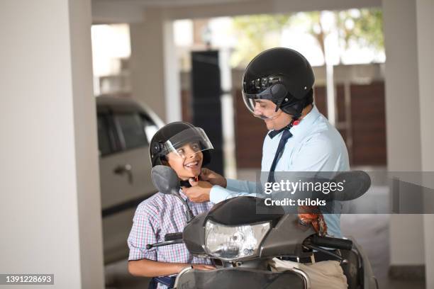 father adjusting helmet of son before leaving for school and office - sports helmet stock pictures, royalty-free photos & images