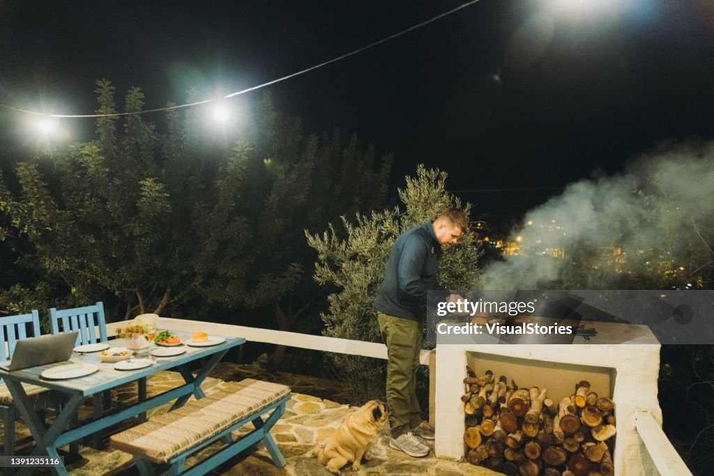 Un homme et un chien profitant d’un pique-nique barbecue avec des hamburgers sur la terrasse de la maison