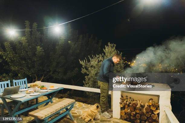 Un Homme Et Un Chien Profitant Dun Piquenique Barbecue Avec Des Hamburgers Sur La Terrasse De La Maison, Photo