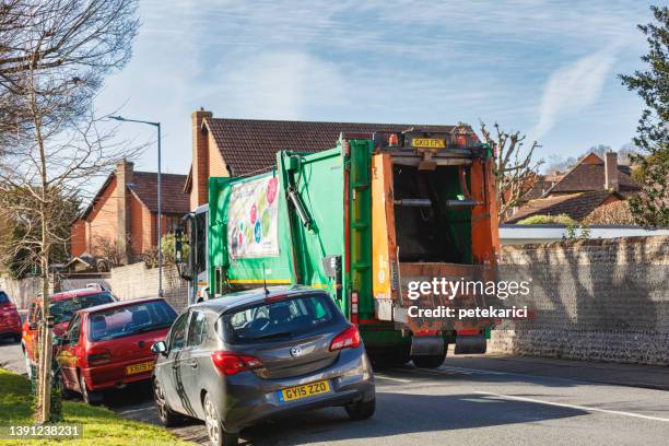 image of a garbage truck driving down a road, the uk - dustbin lorry stock pictures, royalty-free photos & images