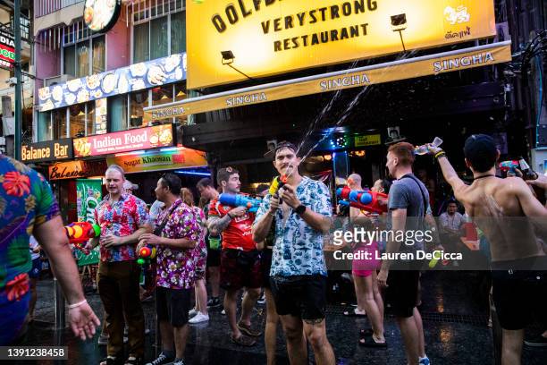 Thai tourists and locals celebrate Songkran by spraying each other with water guns and partying on Khaosan Road on April 13, 2022 in Bangkok,...