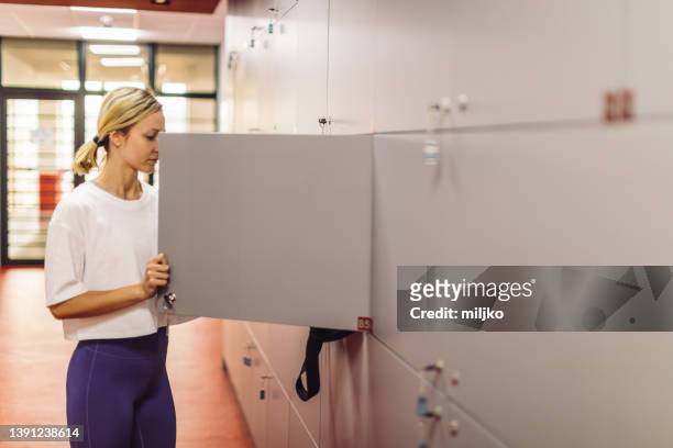 young woman preparing and dressing up for training in gym - sports equipment locker stock pictures, royalty-free photos & images