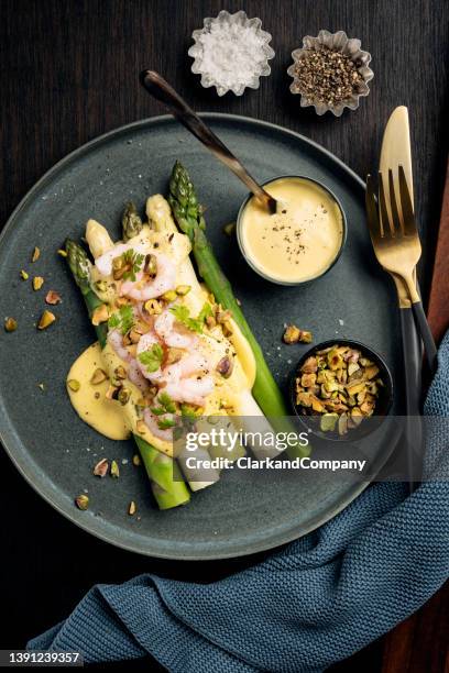 grüner und weißer spargel mit garnelen, pistazien in einer hollandaise-sauce - spargel stock-fotos und bilder