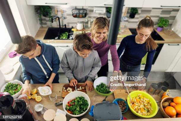 mãe e filhos preparando saladas saudáveis em casa. - restos - fotografias e filmes do acervo