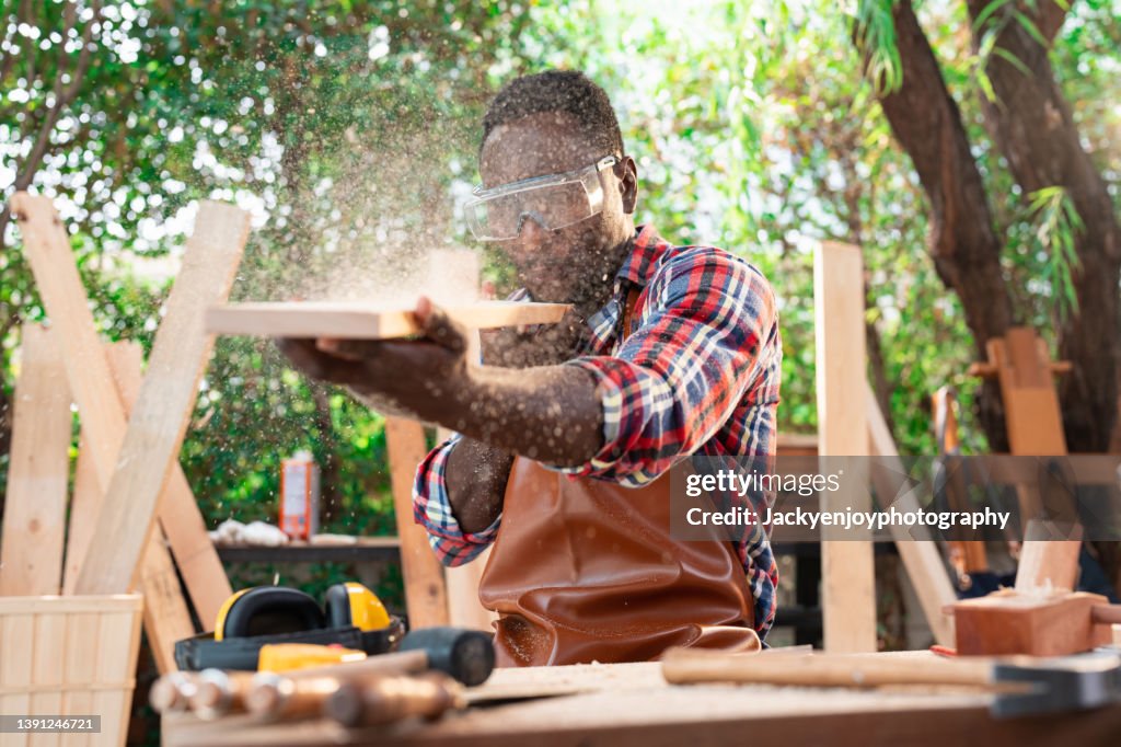 Young handosme carpenter blowing off sawdust