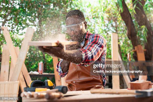 young handosme carpenter blowing off sawdust - sawdust stock pictures, royalty-free photos & images