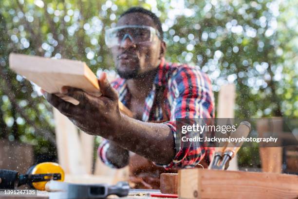 carpenter blows off wood dust cloud by wooden billet. - blowing sawdust stock pictures, royalty-free photos & images