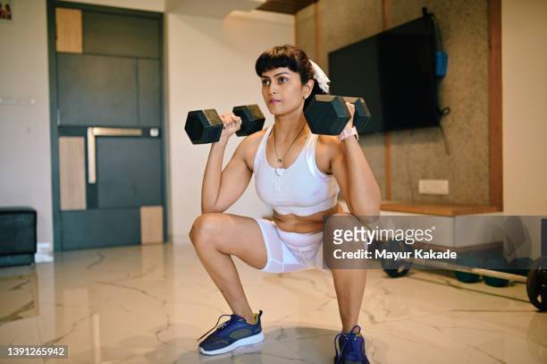 fit woman in sportswear performing strength training at home - weight training foto e immagini stock