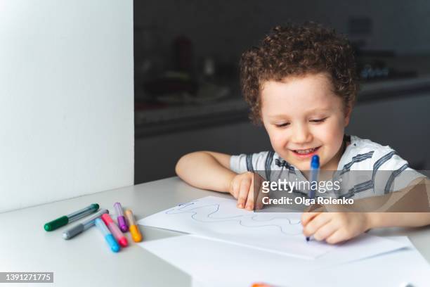 little curly boy draws with a felt-tip pen with left hand, close up portrait - felt tip pen bildbanksfoton och bilder