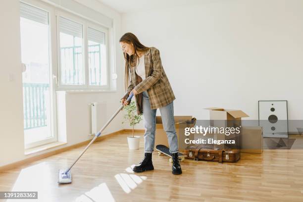 giovane donna che pulisce e prepara la sua casa per trasferirsi - scopa foto e immagini stock