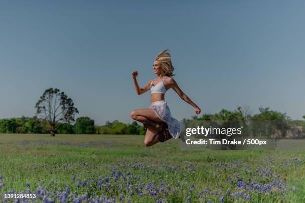 country dance,full length of woman jumping on field against sky - drake one dance stockfoto's en -beelden