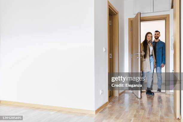 excited young couple opening front door of new home, couple opening door and walking in empty lounge of new home , complete walk-through of their new house - home door stock pictures, royalty-free photos & images