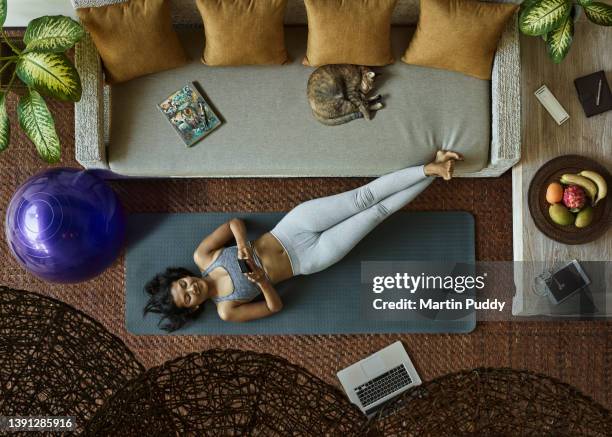 asian woman using phone while practicing yoga during home workout in living room, aerial view - cat laptop stock pictures, royalty-free photos & images