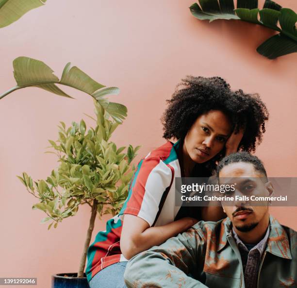 a beautiful pair strike a pose and look directly into the camera - fashion model couple stock pictures, royalty-free photos & images