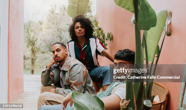 three beautiful young, fashionable people with a cool attitude pose in an outdoor area - three people fotografías e imágenes de stock