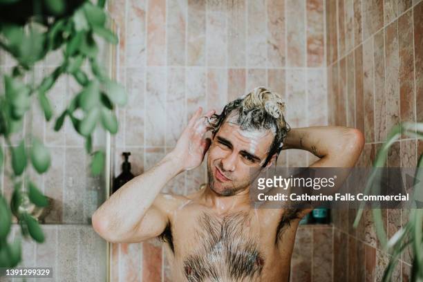 portrait of a man washing his hair in the shower. he looks at the camera. - homem banho imagens e fotografias de stock