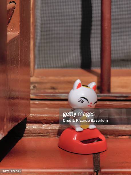 Maneki Neko, oriental lucky charm, with solar panel, placed on the eaves of an old window.