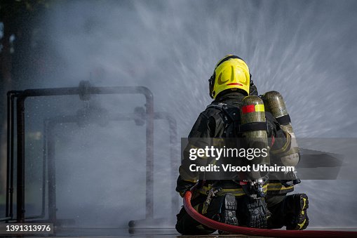 Firefighters fighting fire during training,Firefighter using extinguisher and spray water from hose for fire fighting. Firefighters fighting fire during training,Firefighter using extinguisher and spray water from hose for fire fighting.