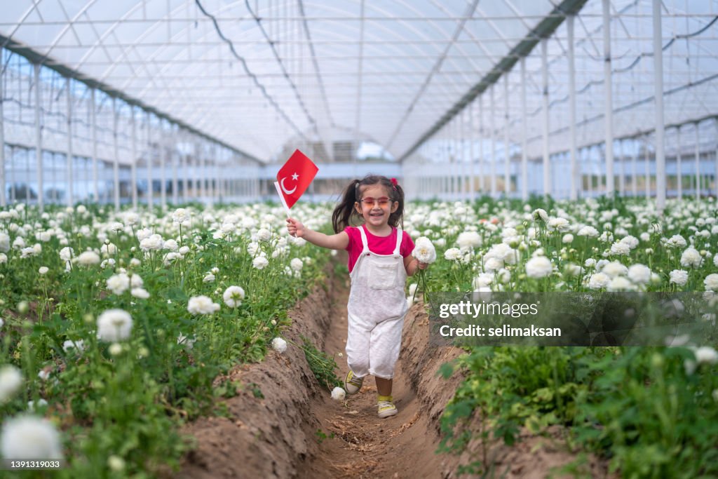 花畑でトルコ国旗を掲げる未就学児の女の子