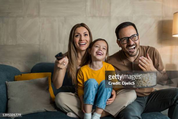 feliz familia joven viendo la televisión juntos en casa. - familia viendo la television fotografías e imágenes de stock