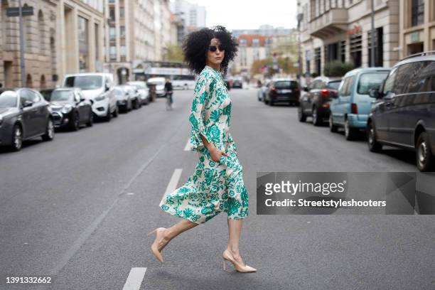 Model and artist Zoe Helali wearing a cream colored blouse with green floral print and a matching midi skirt by Miss Goodlife sunglasses by Armani...