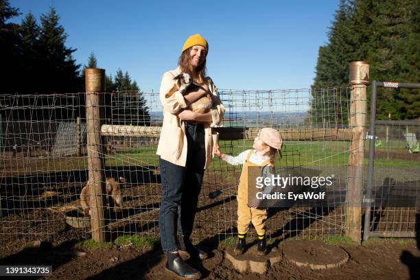 portrait of mother and toddler on farm holding baby goat - 2022 a funny thing stock pictures, royalty-free photos & images