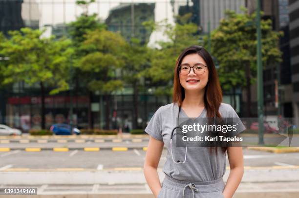 a portrait of a female southeast asian healthcare worker wearing scrub suit outdoors - filipino ethnicity and female not male fotografías e imágenes de stock