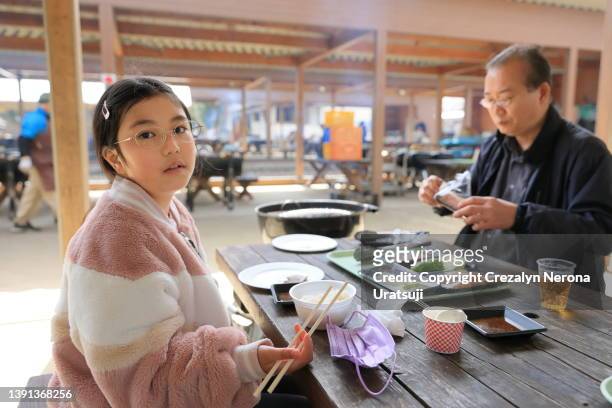 father and child eating bbq together in new normal style - asian child with new glasses stockfoto's en -beelden