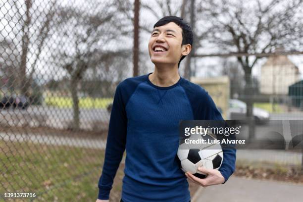 smiling young chinese man with a soccer ball on sports court - china games day 1 fotografías e imágenes de stock