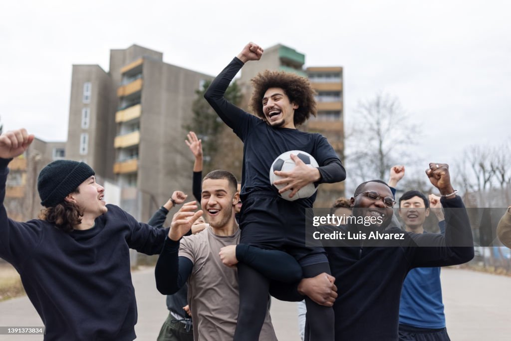 Winning football team cheering on playing field